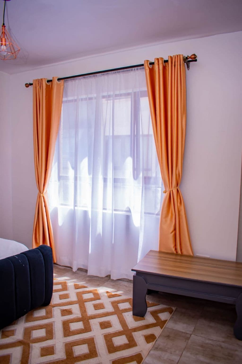 A room with a bed, a bench, and curtains.