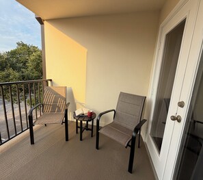 A balcony with two chairs, a small table, and a red cup. - Safe & Sound (Biloxi)