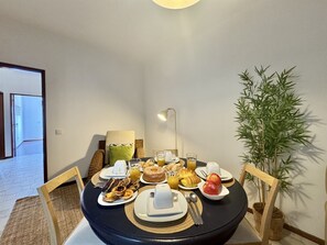 A dining table with breakfast items, a lamp, and a potted plant. - Faro Central 1 by Homing (Faro)