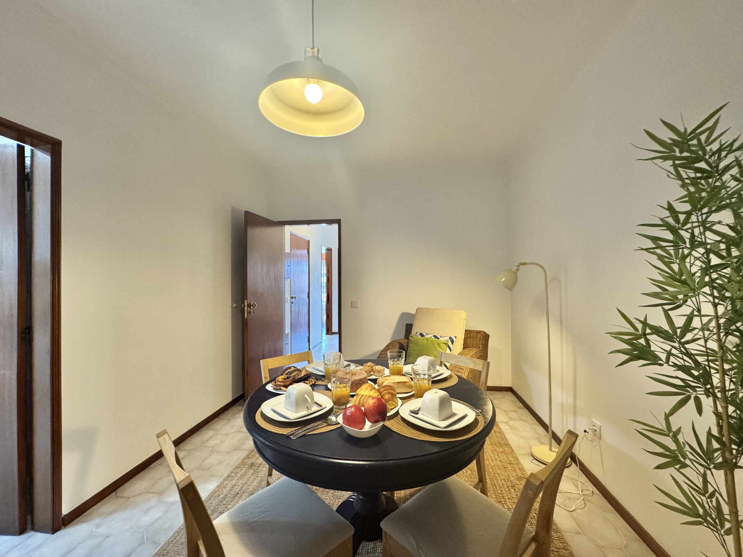 A dining area with a round table, chairs, and a hanging light fixture.