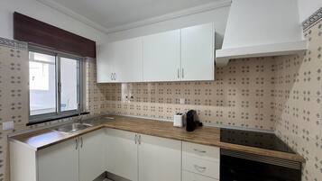 A kitchen with white cabinets, a window, a sink, and a stove.