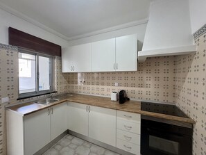 A kitchen with white cabinets, a window, a sink, and a stove. - Faro Central 1 by Homing (Faro)