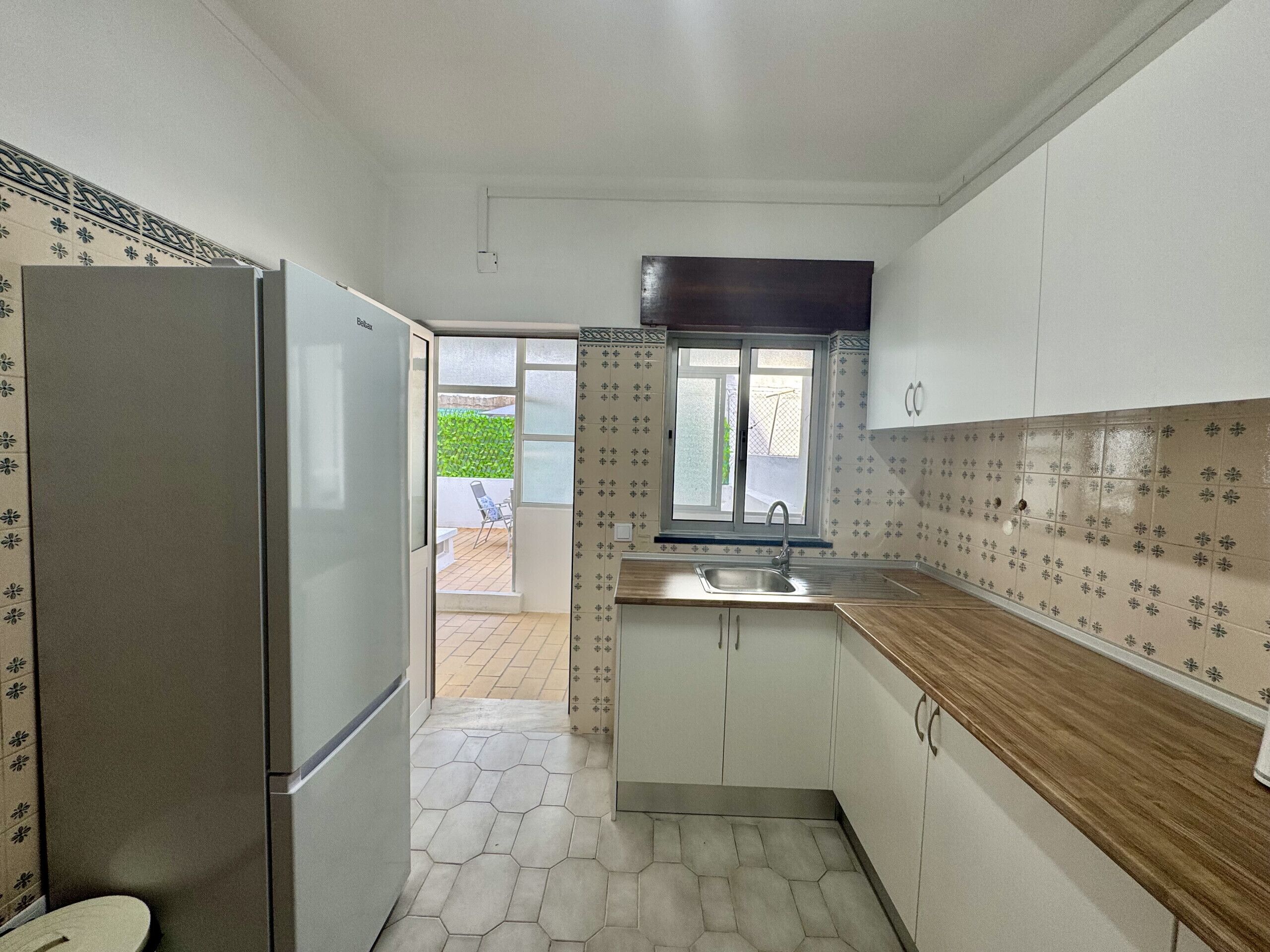 A compact kitchen with a refrigerator, a sink, and cabinets.