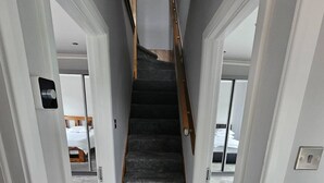 A narrow hallway with a carpeted staircase leading to a room with a bed. - Serene 5-bedroom House in Staines-upon-thames With Garden (Staines)