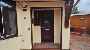 A residential entrance with a dark brown door, a small porch area, and a brick pathway leading to the entrance. - Serene 5-bedroom House in Staines-upon-thames With Garden (Staines)