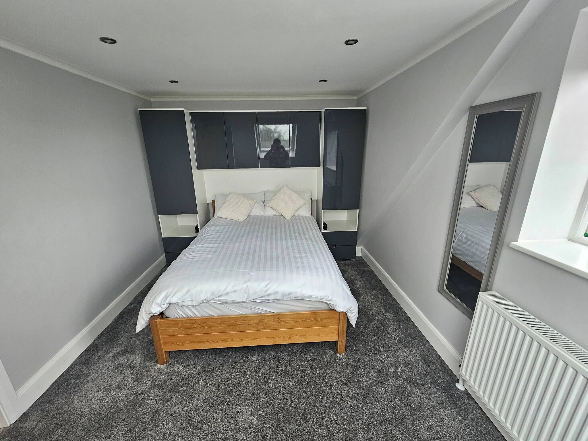 Ein Schlafzimmer mit Bett, Fenster und Heizkörper.