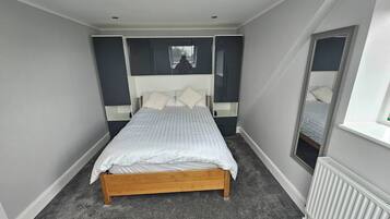 Ein Schlafzimmer mit Bett, Fenster und Heizkörper.