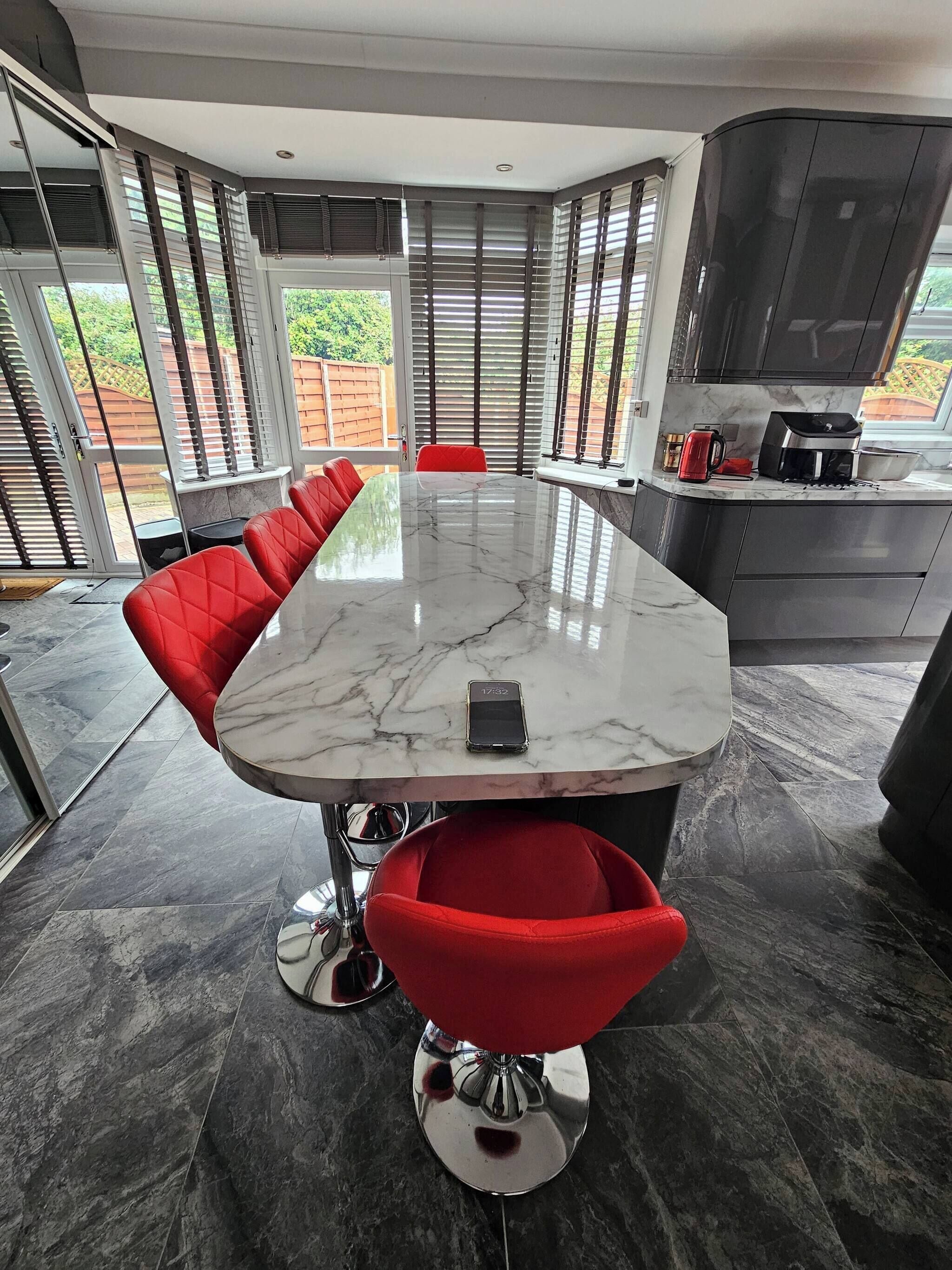 A modern kitchen with a large island, red chairs, and a dining table.