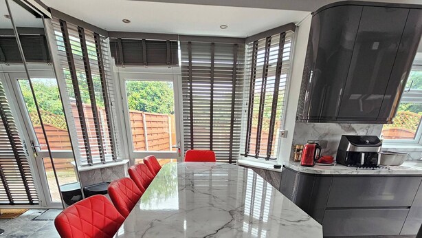 A modern kitchen with a large island, red chairs, and a dining table. - Serene 5-bedroom House in Staines-upon-thames With Garden (Staines)
