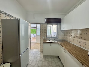 A compact kitchen with a refrigerator, a sink, and cabinets. - FARO CENTRAL 1 by HOMING (Faro)