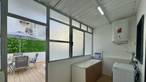 Eine kompakte Küche mit integriertem Kühlschrank, Durchlauferhitzer und Blick auf eine Terrasse.
