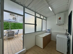 A compact kitchen with a built-in refrigerator, a water heater, and a window overlooking a patio area. - FARO CENTRAL 1 by HOMING (Faro)