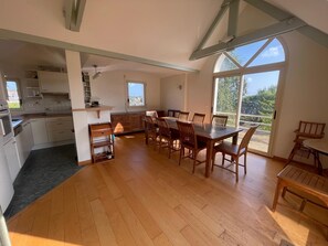 Een ruime keuken met houten kastjes en een eethoek met een grote tafel en stoelen.
