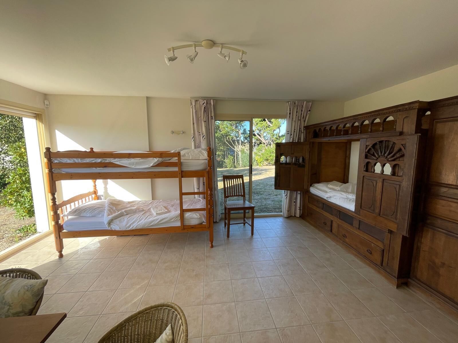 A room with bunk beds, a wooden cabinet, a chair, and a table.