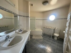 Een badkamer met twee wastafels, een bad en een toilet.