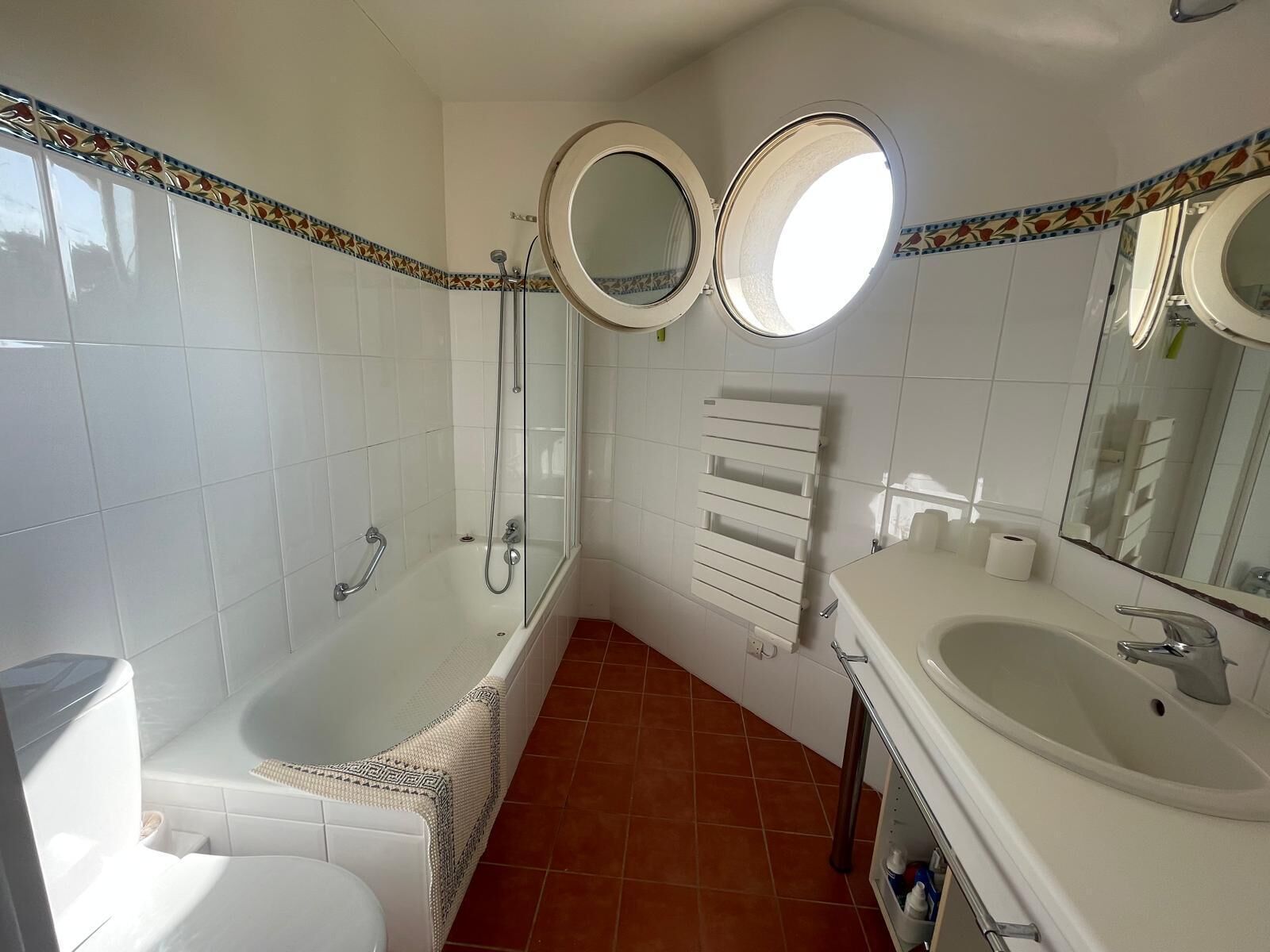 A bathroom with a bathtub, a toilet, a sink, and two mirrors.