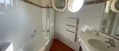 A bathroom with a bathtub, a toilet, a sink, and two mirrors.
