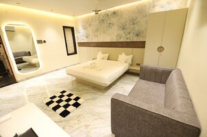 Un dormitorio moderno con una cama grande, un sofá, una alfombra a cuadros y un espejo.