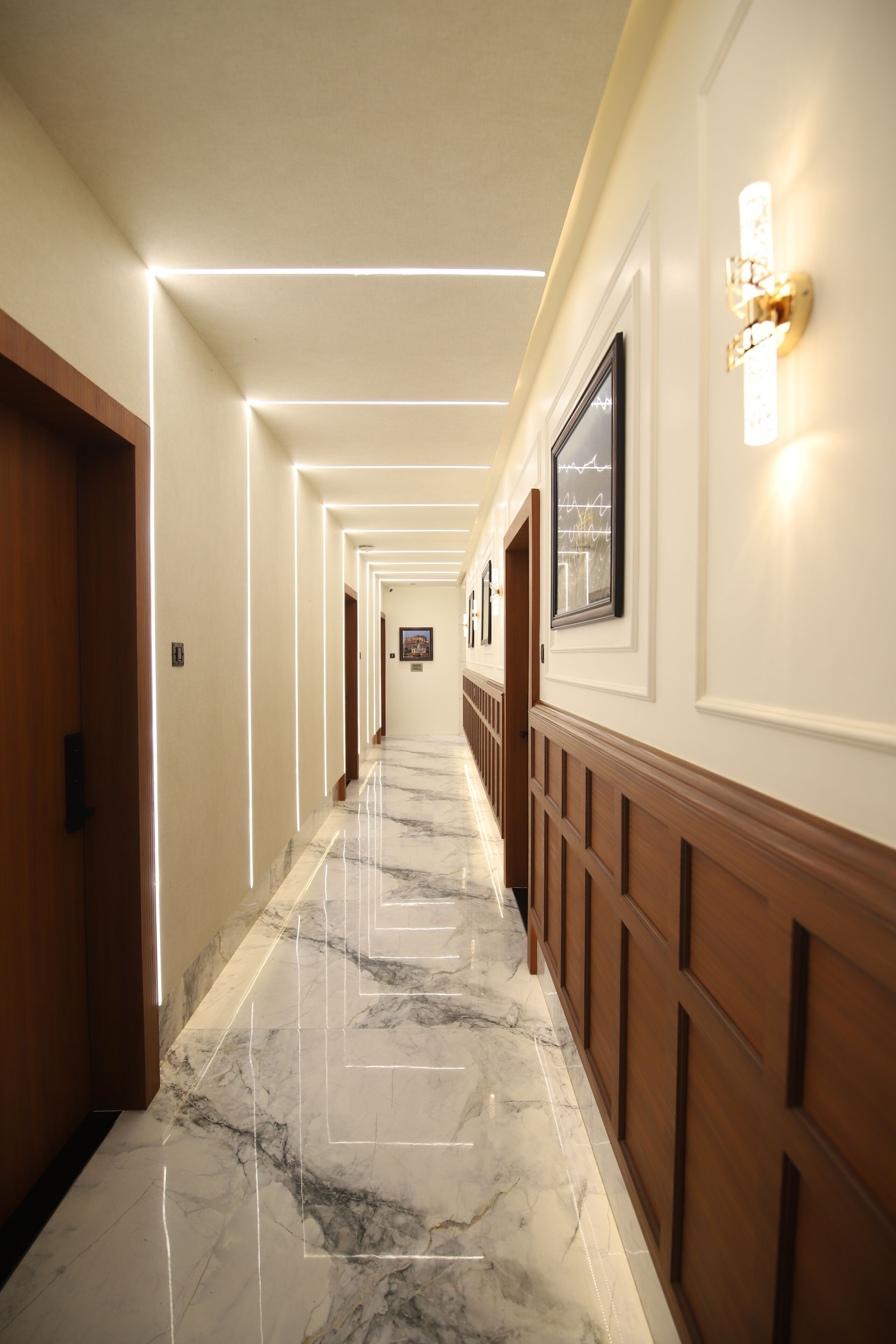 Un corridoio d'hotel con pavimento in marmo, pannelli in legno e quadri appesi alle pareti.