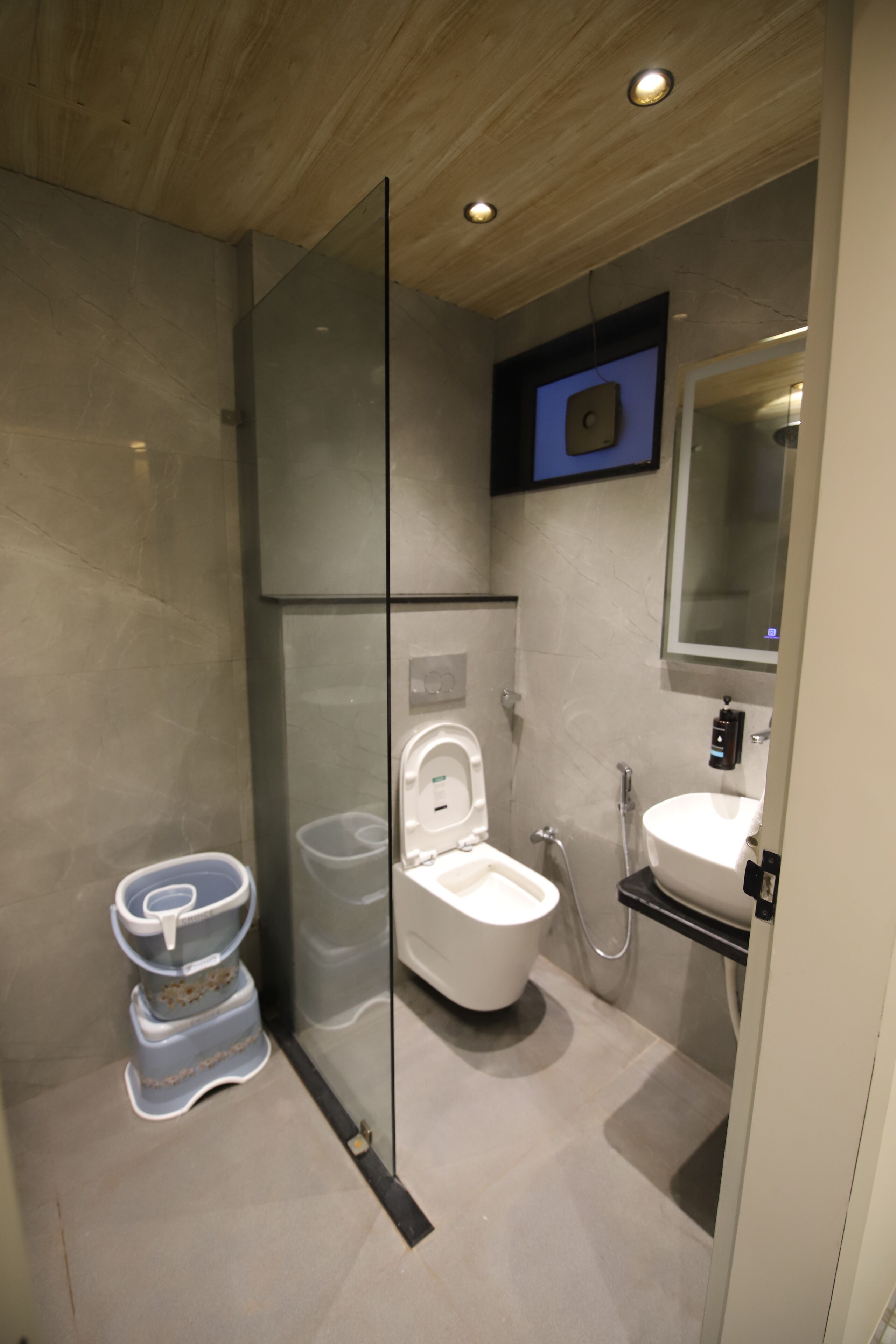 A modern bathroom with a glass partition, a toilet, a bidet, and a sink.