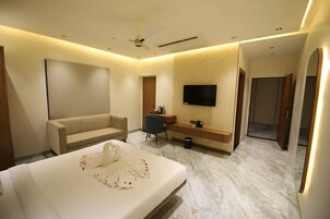 A hotel room with a bed, a sofa, a desk, a television, and a bathroom.