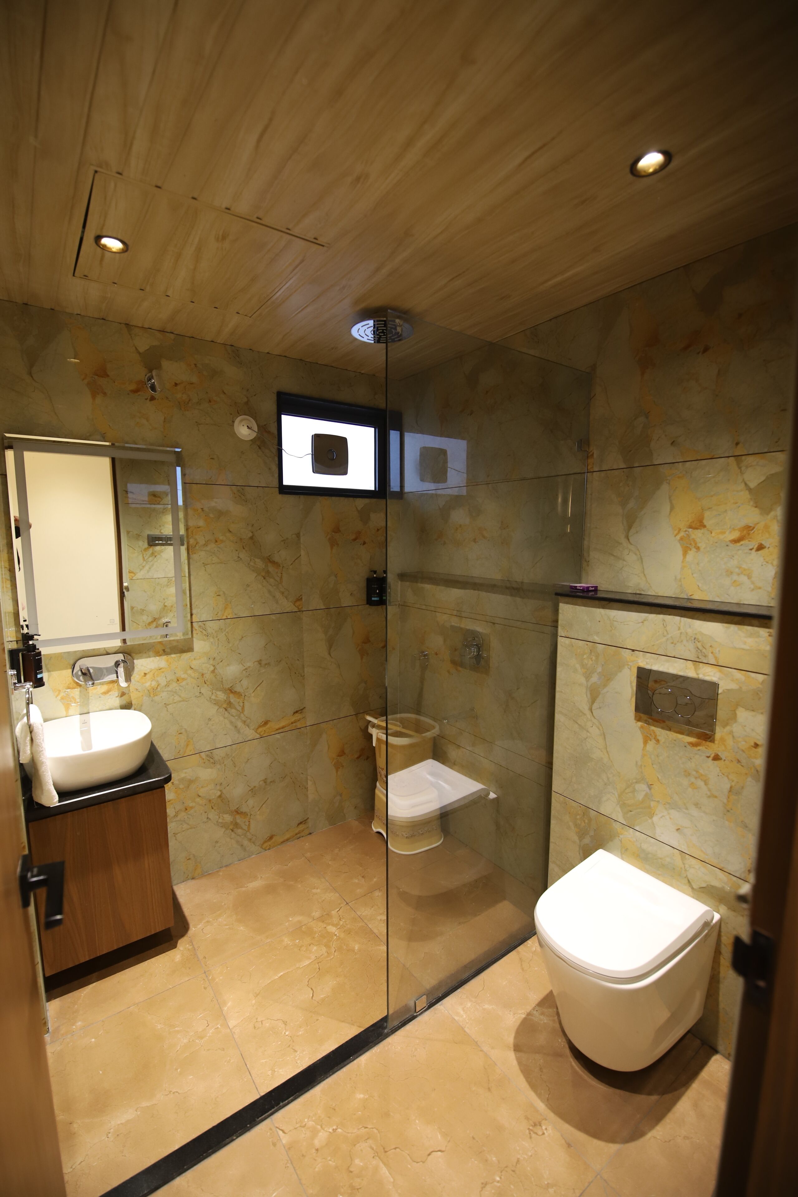 A modern bathroom with a glass-enclosed shower, a toilet, and a sink with a mirror above it.