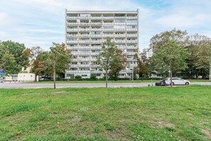 Um edifício residencial de vários andares com fachada uniforme, rodeado por uma área gramada e árvores.