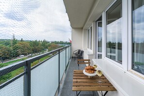 En balkong med utsikt över en trädgård och ett bord med mat och dryck.