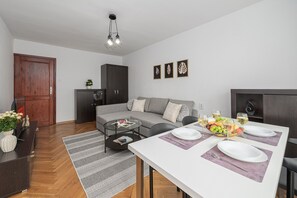 Uma sala de estar moderna com sofá, mesa de centro e área de jantar posta para refeição.