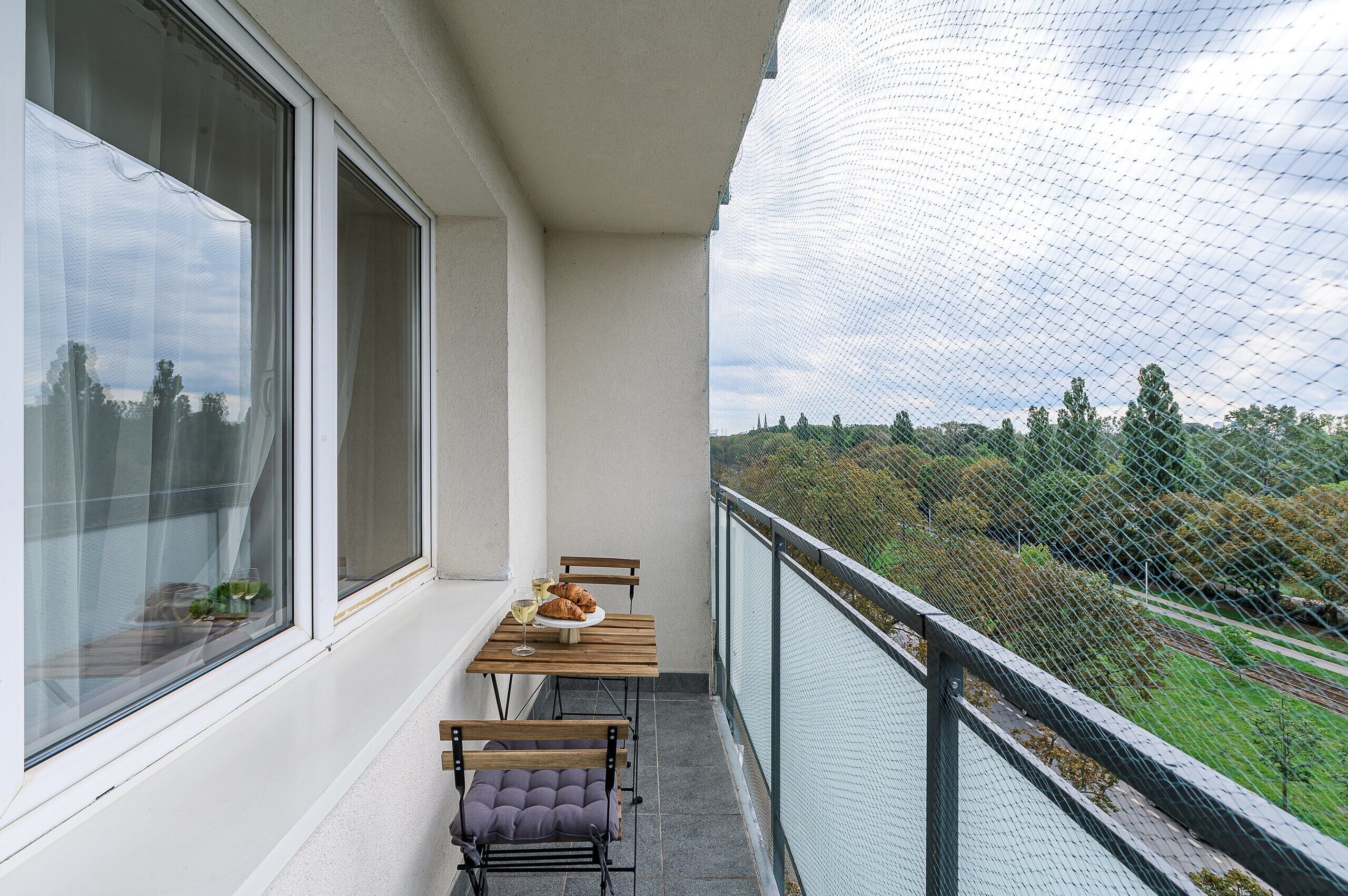 A balcony with a table, two chairs, and a bench.