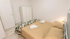 Ein Hotelzimmer mit einem Bett, einem Kleiderschrank und einem Nachttisch mit Lampe.