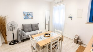 Ein modernes Wohnzimmer mit einer Couch, einem Esstisch und einem Ventilator.