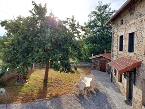 A stone building with a tiled roof, a gravel pathway, and a table with chairs outside. - Country house - 15 guests - Loire Valley (Retournac)