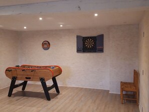 Ein Zimmer mit einem Kicker, einer Dartscheibe und einer Wanddekoration mit Pizza-Motiv.