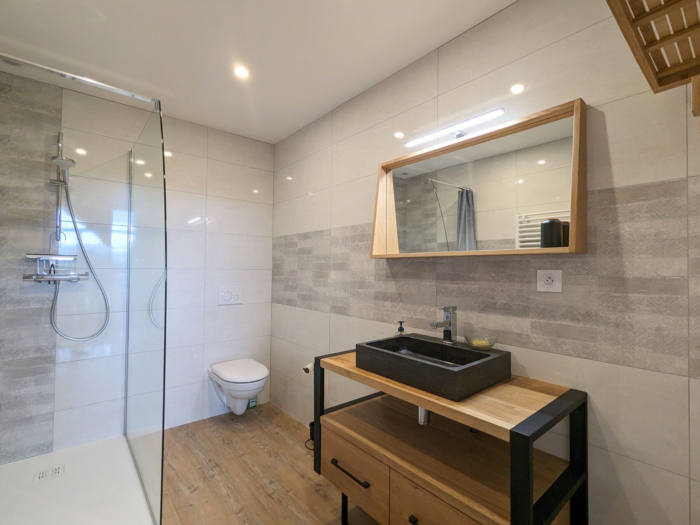 A modern bathroom with a glass-enclosed shower, a toilet, and a vanity with a black sink.