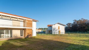 A modern two-story house with a balcony, a fenced yard, and a clear blue sky. - Modern apartment with parking - 4 guests (Mimizan)