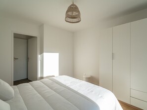 Ein Schlafzimmer mit einem großen Bett, einem Kleiderschrank und einer Pendelleuchte.