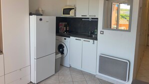 Eine kleine Küche mit Waschmaschine, Mikrowelle und Spüle.
