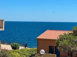 A coastal property with a red-tiled roof, a balcony, and a clear view of the sea. - Charming sea view T2 with private parking (Collioure)