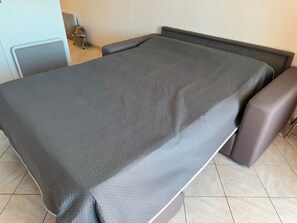 A bed with a grey bedspread and two brown armchairs. - Charming sea view T2 with private parking (Collioure)