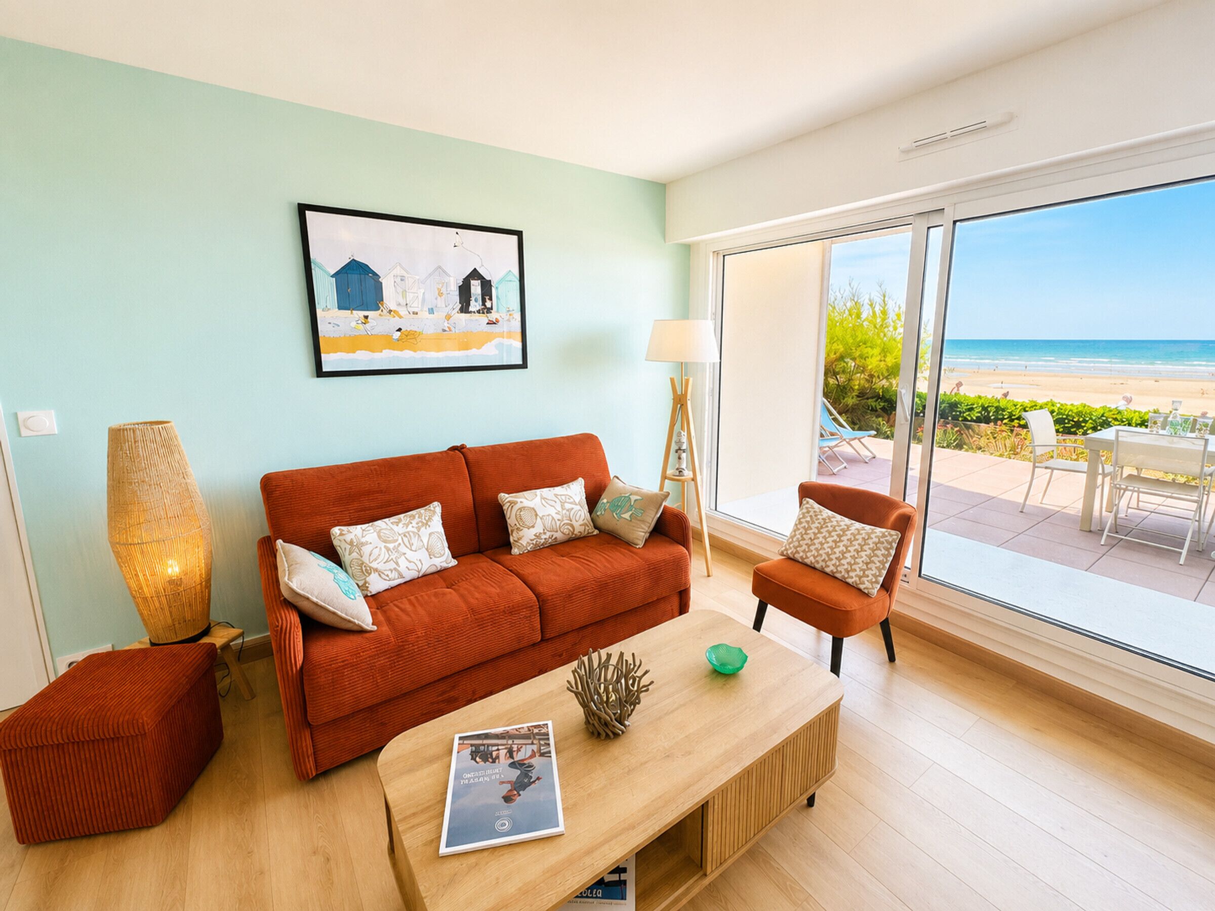 A living room with a sofa, a coffee table, and a view of the beach.