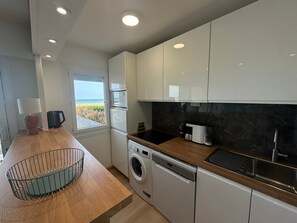 A modern kitchen with built-in appliances, a window with a view, and a wooden countertop. - Apartment, sea view, pets welcome - 4 guests (Cabourg)