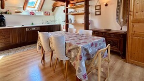 Een landelijke keuken met houten balken, een eettafel met stoelen en een raam boven de spoelbak.