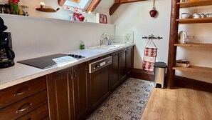Een keuken met dakraam, houten balken, een inbouwvaatwasser en een hangende pannendroger.