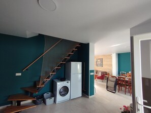 Un espace de vie compact comprenant un escalier, un lave-linge et un coin repas.