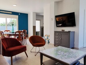 Una sala de estar con televisor, comedor y una mesa con mapa.