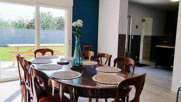 Un coin repas avec une table ronde, des chaises et un vase rempli de fleurs.