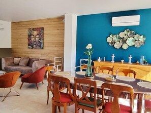 Comedor con mesa de madera, sillas y una pared azul decorativa.