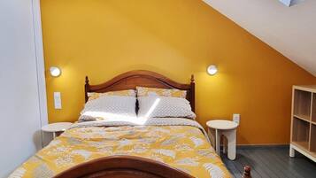 Een slaapkamer met een schuine plafond, een houten bed, twee nachtkastjes en een inbouwkast.