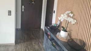 Ein Flur mit dunklem Holzboden, einer dunklen Holztür und einer Wand mit vertikalen Holzleisten.
